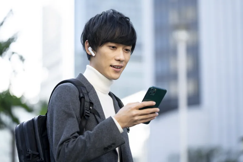 イヤホンをしてスマホの画面を見る若い男性