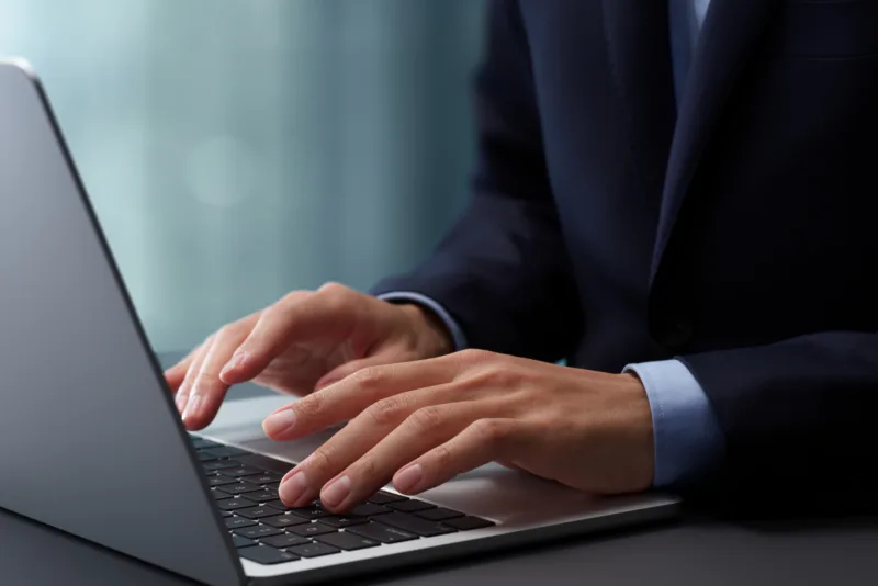 ノートパソコンのキーボードをタイピングする手のアップ